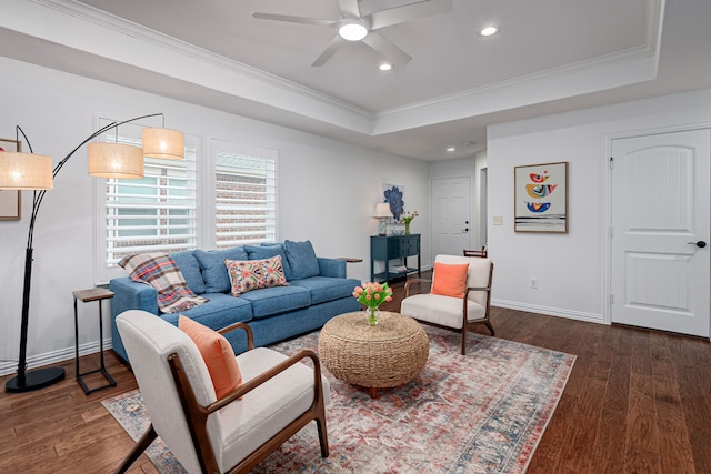 living area with baseboards, crown molding, a tray ceiling, and dark wood-type flooring