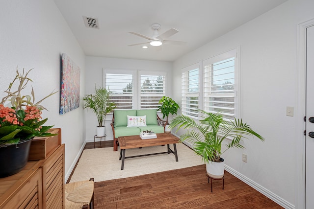 sitting room with a ceiling fan, visible vents, baseboards, and wood finished floors