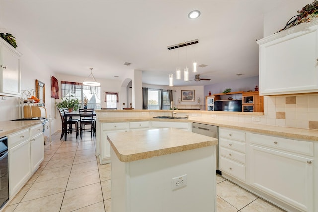 kitchen featuring sink, a kitchen island, decorative light fixtures, kitchen peninsula, and decorative backsplash