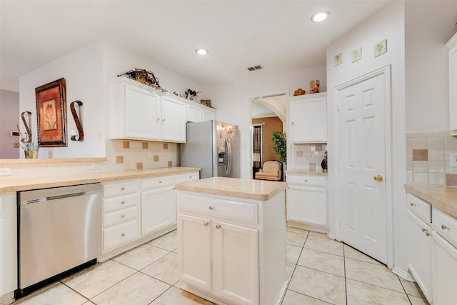 kitchen with appliances with stainless steel finishes, white cabinets, a center island, and light tile patterned floors