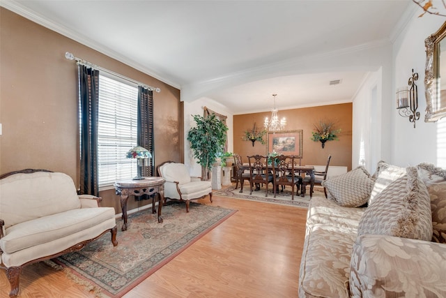 living room with crown molding, plenty of natural light, a chandelier, and light hardwood / wood-style flooring