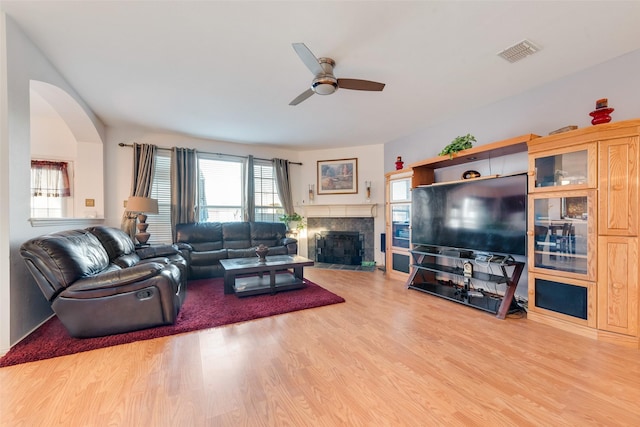 living room with a tile fireplace, hardwood / wood-style floors, and ceiling fan