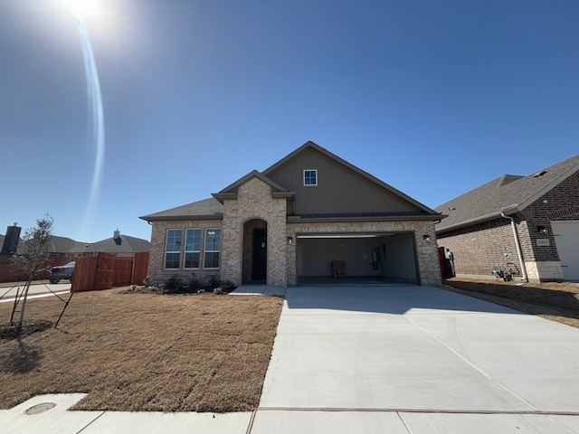 view of front of home with fence, brick siding, a garage, and driveway