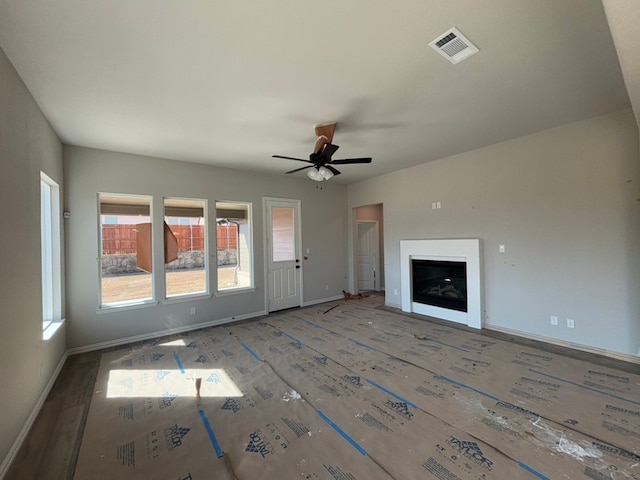 unfurnished living room with wood finished floors, a fireplace, visible vents, and baseboards