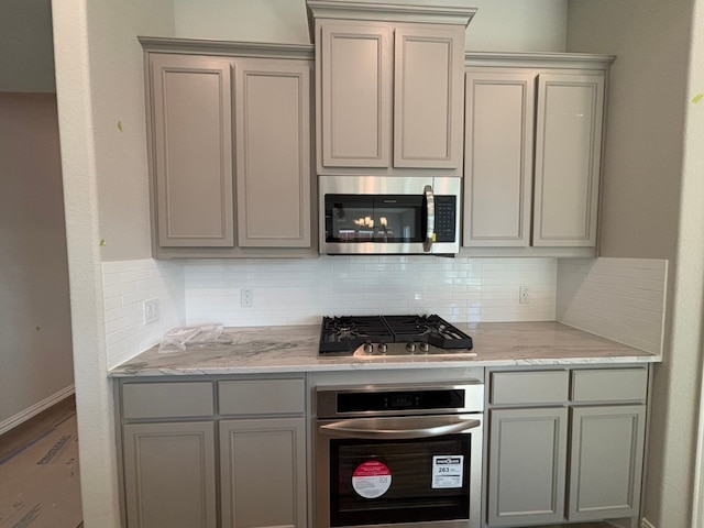 kitchen with stainless steel appliances, tasteful backsplash, and gray cabinetry