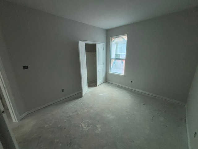 unfurnished bedroom with baseboards, a closet, and concrete flooring