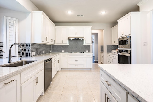 kitchen with light tile patterned flooring, tasteful backsplash, sink, white cabinets, and stainless steel appliances