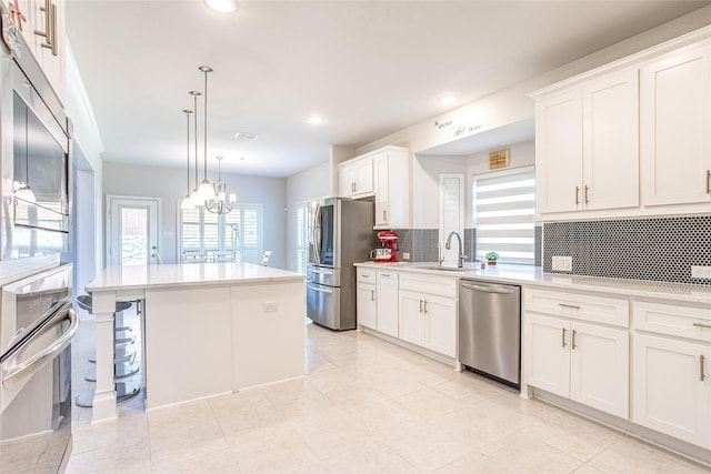 kitchen featuring tasteful backsplash, stainless steel appliances, white cabinets, and a kitchen island