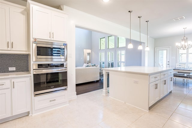 kitchen featuring white cabinetry, decorative backsplash, decorative light fixtures, and appliances with stainless steel finishes