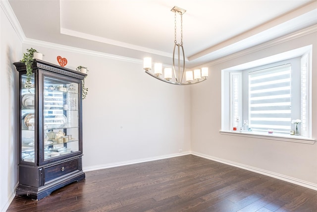 spare room featuring a chandelier, dark hardwood / wood-style flooring, a raised ceiling, and crown molding