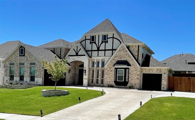 tudor-style house featuring a garage and a front yard