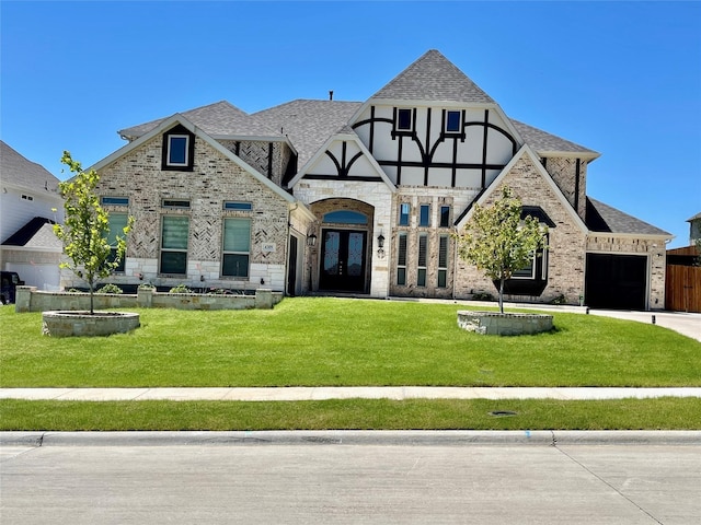 tudor-style house with a garage, a front yard, and french doors