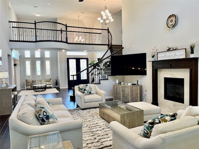 living room with a high ceiling, wood-type flooring, a notable chandelier, and a fireplace