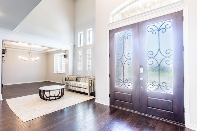 entrance foyer with french doors, dark wood-type flooring, and an inviting chandelier