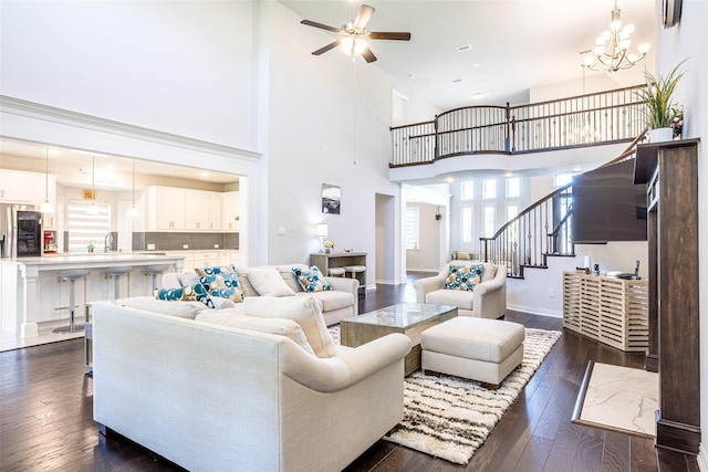 living room with sink, a towering ceiling, ceiling fan with notable chandelier, and dark hardwood / wood-style flooring