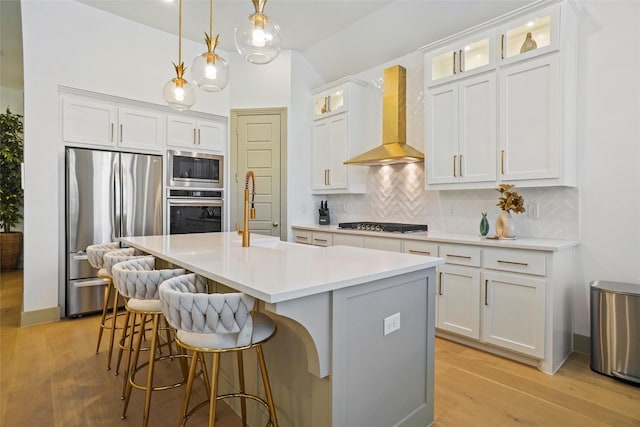 kitchen featuring white cabinetry, appliances with stainless steel finishes, and wall chimney range hood