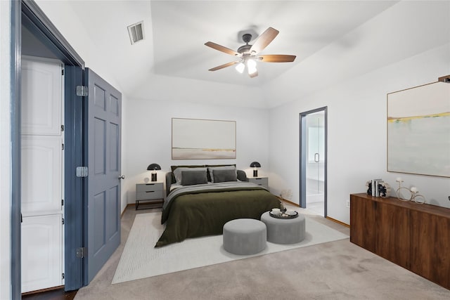 bedroom featuring ceiling fan, light colored carpet, connected bathroom, and a tray ceiling