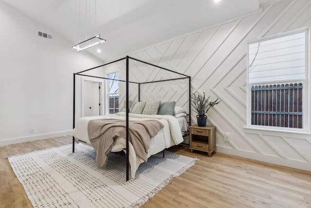 bedroom with vaulted ceiling and light hardwood / wood-style flooring