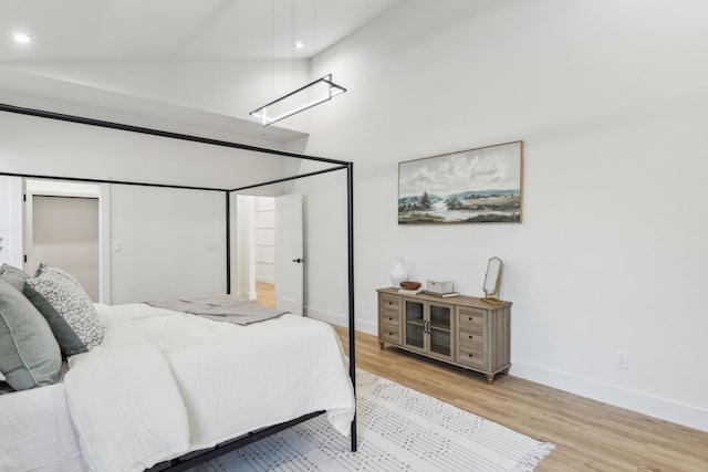 bedroom with high vaulted ceiling, a closet, and light wood-type flooring