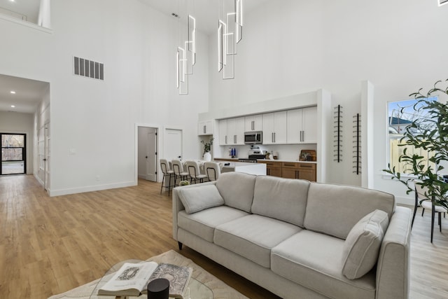 living room with light wood-type flooring and a high ceiling