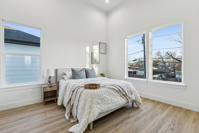 bedroom with a high ceiling and light wood-type flooring