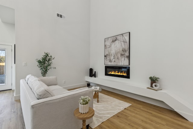 living room featuring hardwood / wood-style flooring, a fireplace, and a high ceiling