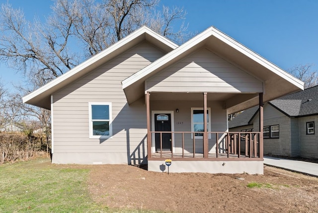 bungalow-style house featuring covered porch and a front lawn