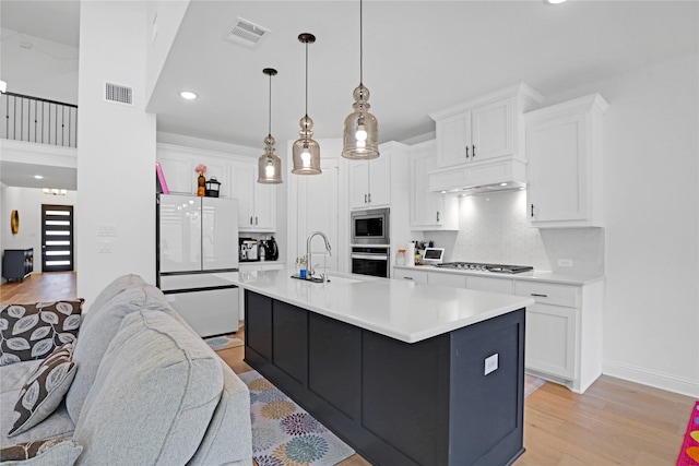 kitchen with tasteful backsplash, appliances with stainless steel finishes, an island with sink, and white cabinets