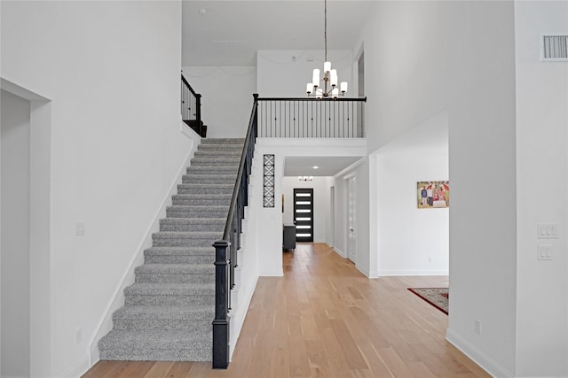 entrance foyer featuring a towering ceiling, wood-type flooring, and a chandelier