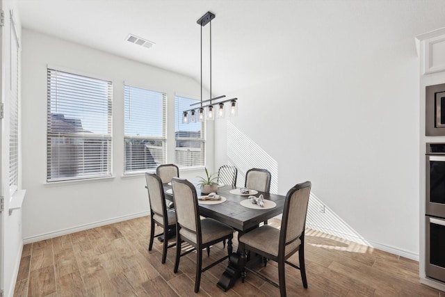 dining room featuring vaulted ceiling and light hardwood / wood-style floors