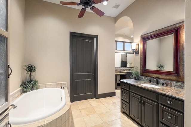 bathroom with a relaxing tiled tub, ceiling fan, vanity, and tile patterned flooring