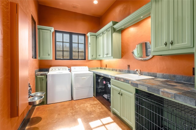 clothes washing area featuring cabinets, sink, and washing machine and dryer