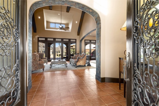 foyer featuring ceiling fan, a towering ceiling, and tile patterned floors