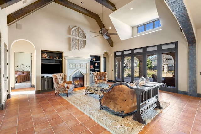 living room featuring built in shelves, a towering ceiling, ceiling fan, and tile patterned flooring