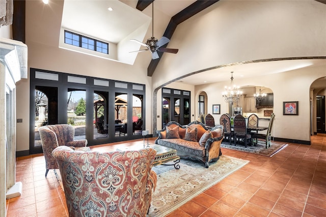 living room with ceiling fan with notable chandelier, a towering ceiling, and tile patterned flooring