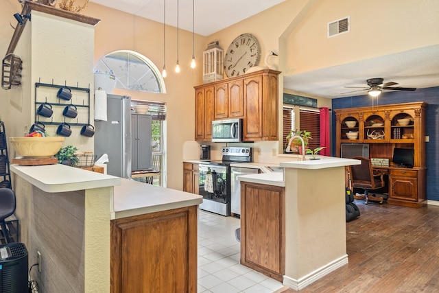 kitchen with sink, a breakfast bar area, hanging light fixtures, kitchen peninsula, and stainless steel appliances