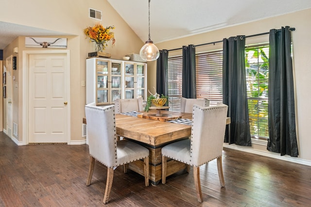 dining room featuring a wealth of natural light, visible vents, lofted ceiling, and dark wood finished floors