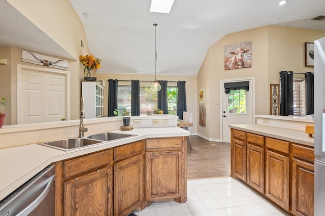 kitchen with lofted ceiling with skylight, decorative light fixtures, sink, stainless steel dishwasher, and light tile patterned floors