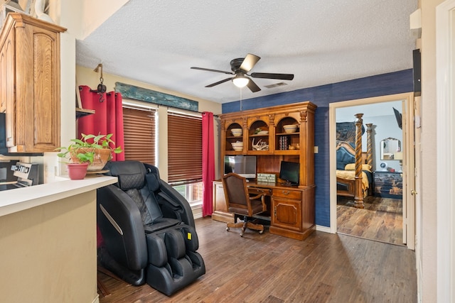 office featuring a ceiling fan, wood finished floors, visible vents, and a textured ceiling