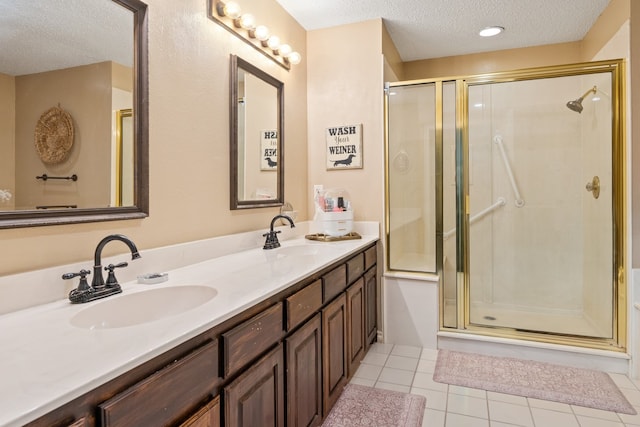 bathroom featuring a sink, a textured ceiling, a shower stall, and tile patterned floors