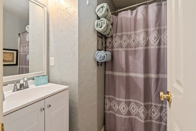 bathroom with a shower with shower curtain, vanity, and a textured wall