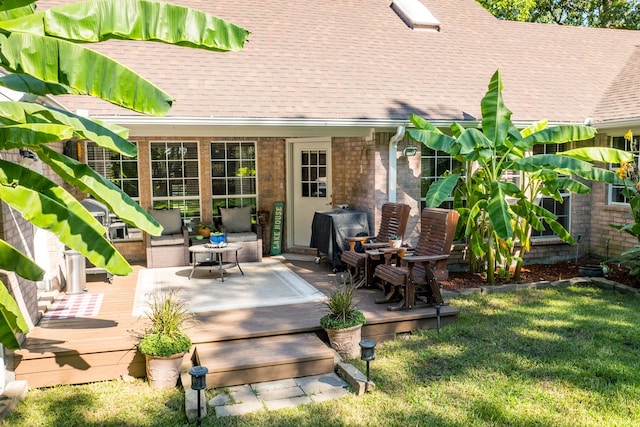 exterior space featuring brick siding, a deck, a yard, and roof with shingles