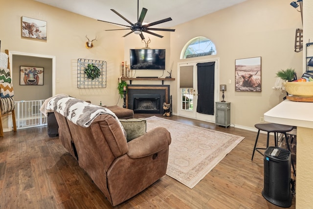 living room featuring dark hardwood / wood-style floors, ceiling fan, and a towering ceiling