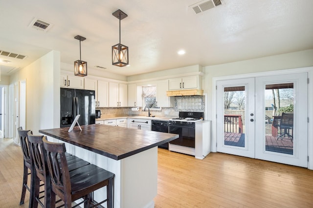 kitchen featuring sink, tasteful backsplash, decorative light fixtures, black appliances, and white cabinets