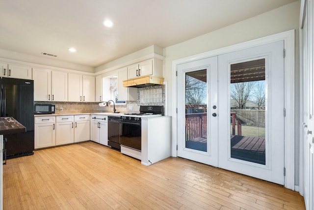 kitchen with french doors, white cabinetry, backsplash, and black appliances