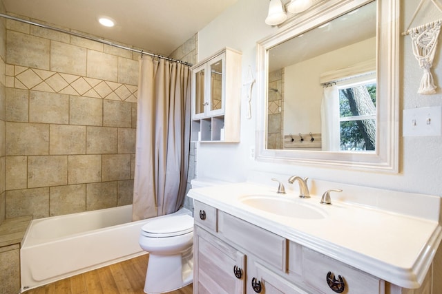 full bathroom with hardwood / wood-style flooring, vanity, shower / tub combo, and toilet