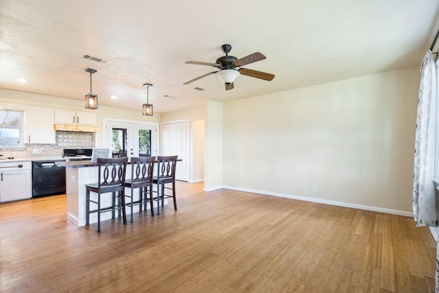 kitchen featuring a breakfast bar, hanging light fixtures, backsplash, black dishwasher, and white cabinets