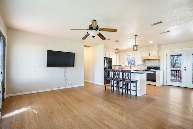 kitchen with a breakfast bar, black refrigerator, white electric range oven, white cabinets, and decorative backsplash