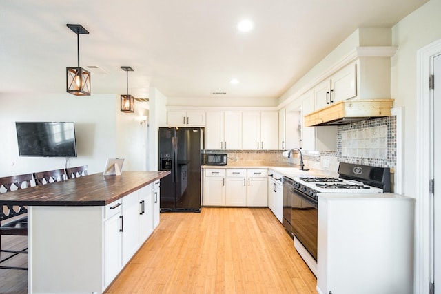 kitchen featuring pendant lighting, white cabinetry, backsplash, black appliances, and a kitchen island