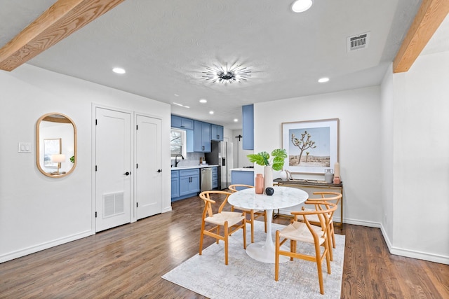 dining area featuring beamed ceiling, dark hardwood / wood-style floors, and sink